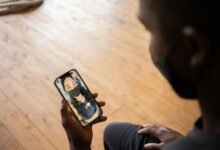 Man video calling his partner during the pandemic wearing masks indoors for safety.
