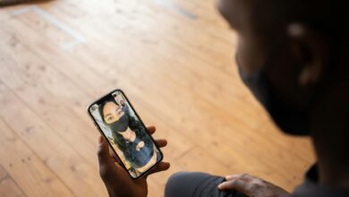 Man video calling his partner during the pandemic wearing masks indoors for safety.